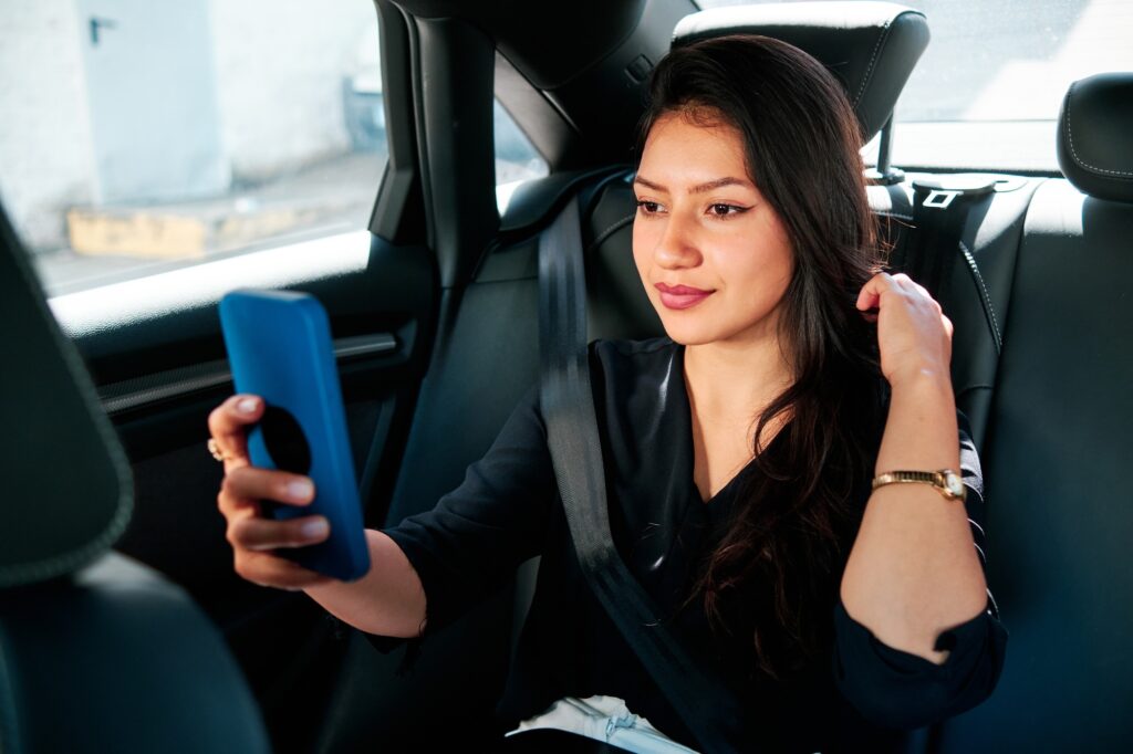 young latin businesswoman using smartphone in her car